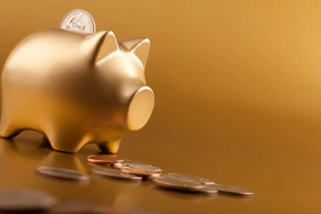 Golden piggy bank with coins, financial savings concept.