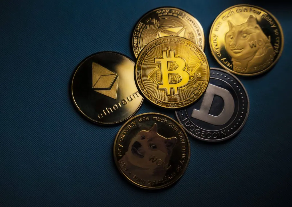 Cryptocurrency coins including Bitcoin, Ethereum, Dogecoin on blue background.