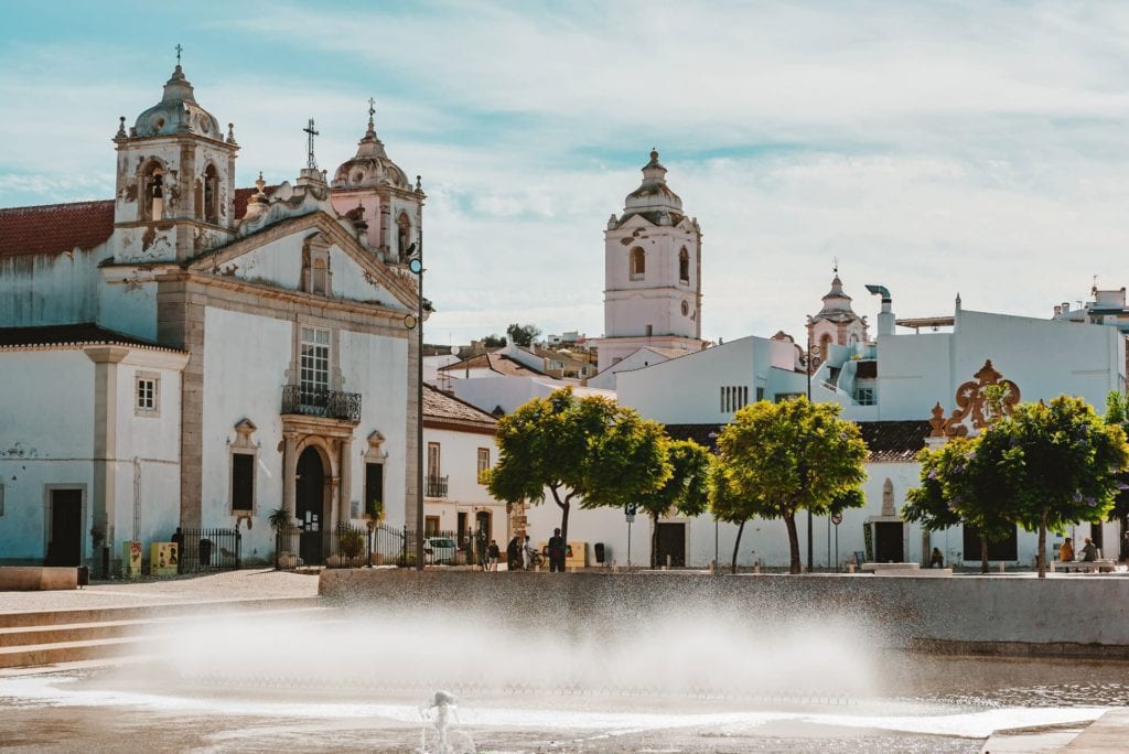 Historic white church in Estoril, Portugal with scenic town square and fountain.