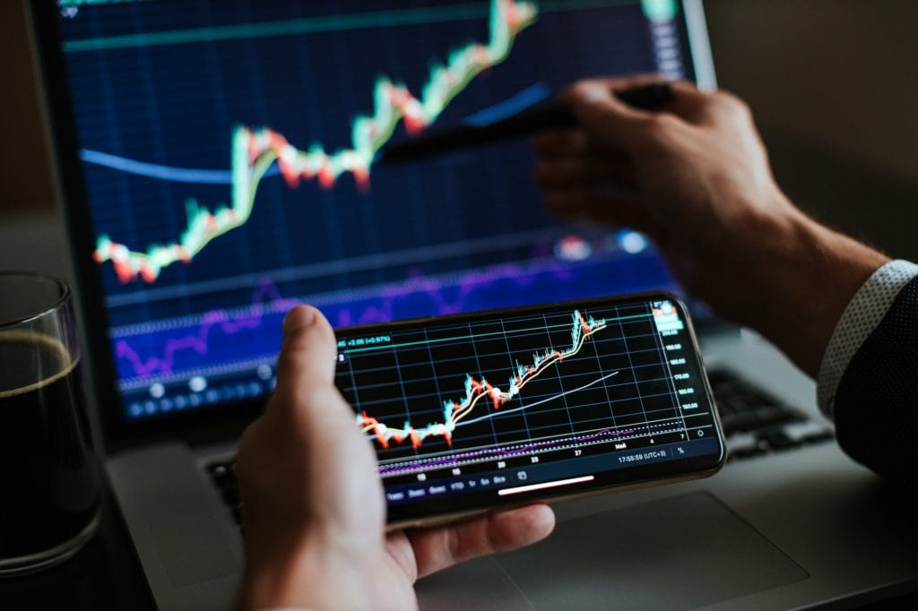 Financial trading analysis on smartphone and computer screens for investment insights.