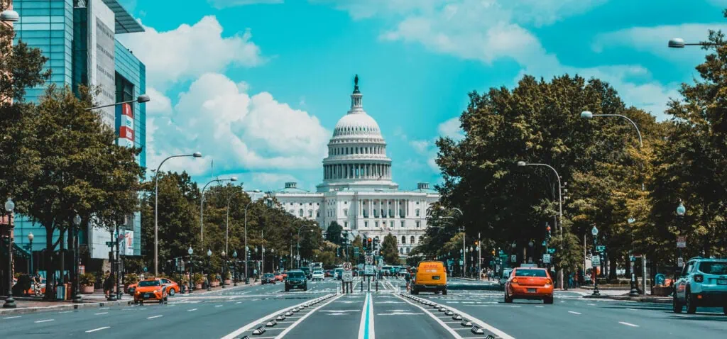 Imposing US Capitol building in Washington DC with surrounding trees and city traffic.