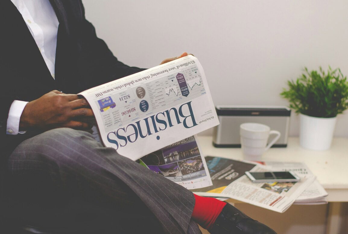 Business news and financial analysis with newspapers in a professional office setting.
