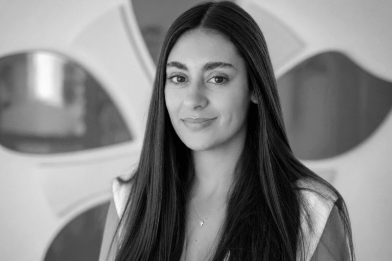 Professional woman with long dark hair smiling in modern office setting.