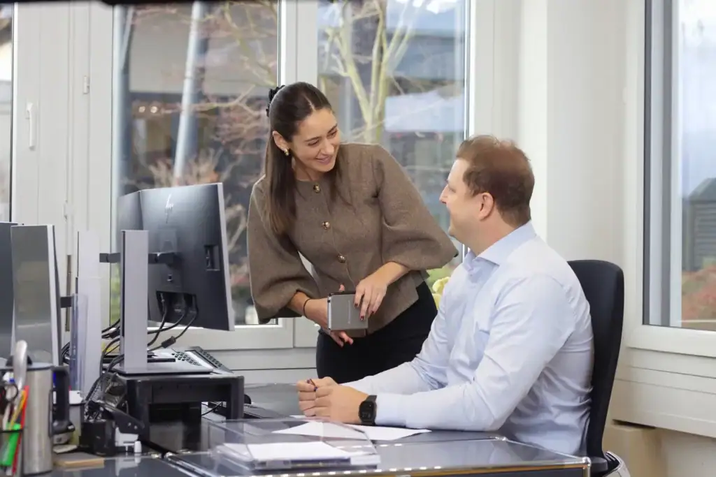 Professional business colleagues discussing in modern office with large windows.