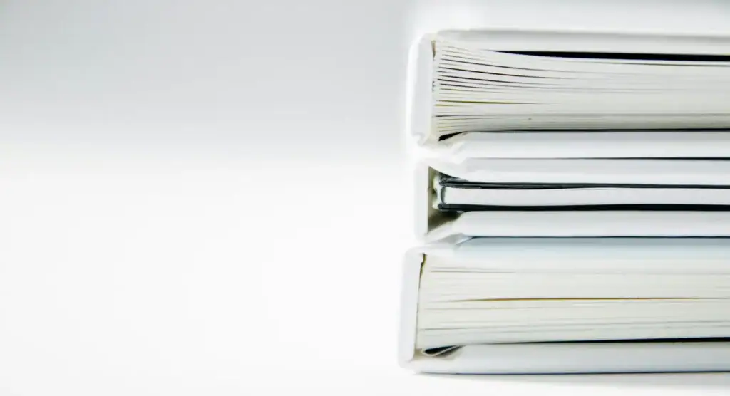 Three thick white document binders stacked on a plain light background