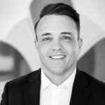 Professional portrait of a smiling man in a suit at Alpen Partners AG office.