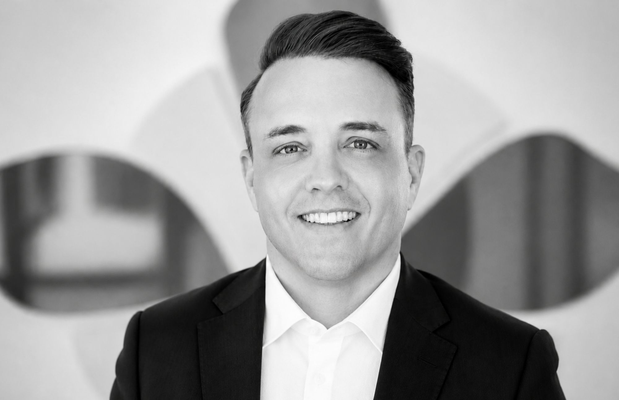 Professional portrait of a smiling man in a suit at Alpen Partners AG office.