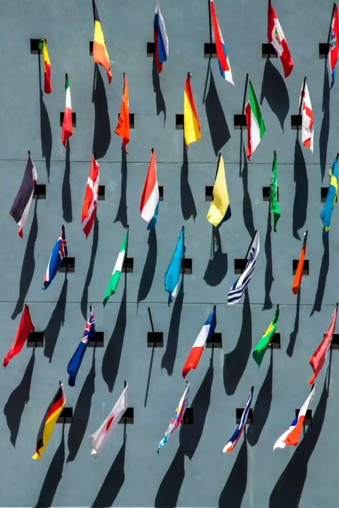 Colourful international flags displayed on a grey surface, aerial perspective.
