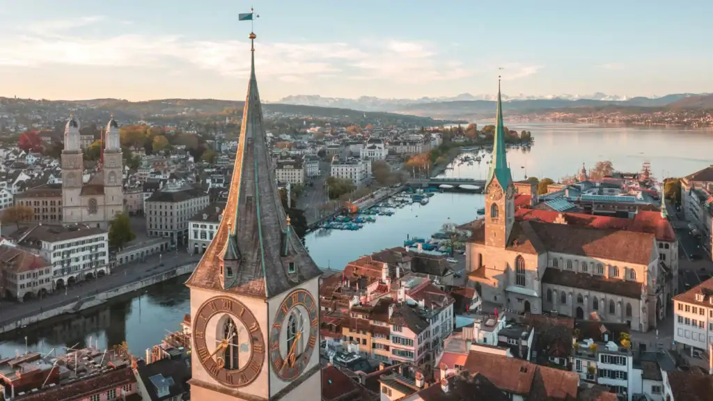 Aerial view of Zurich with historic churches and Lake Zurich in the background.
