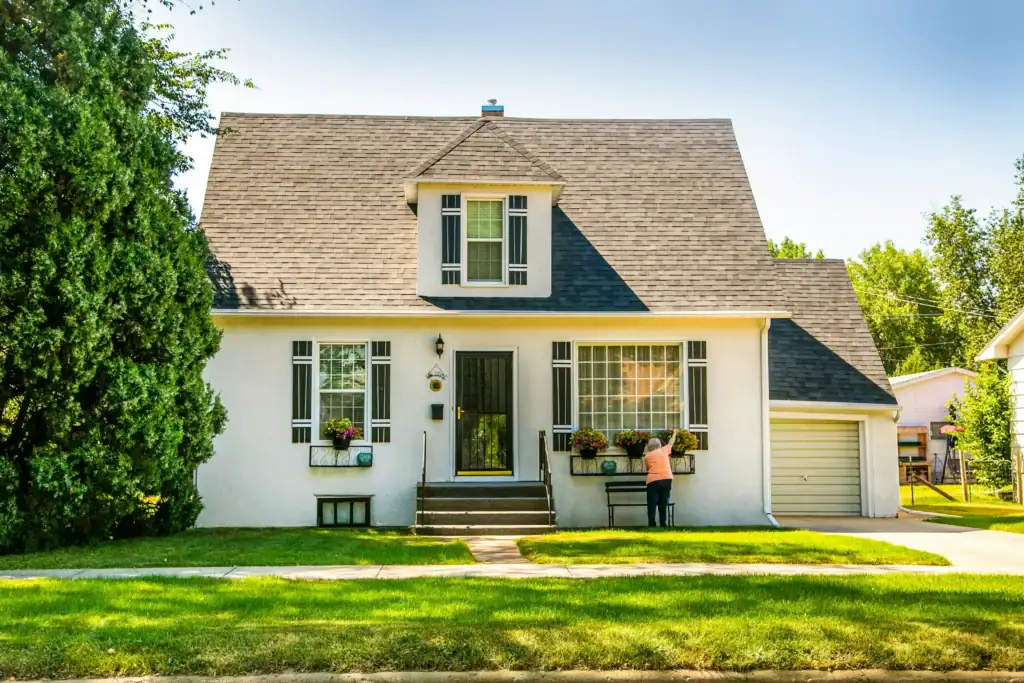 Detached white house with a front lawn and garden on a quiet residential street