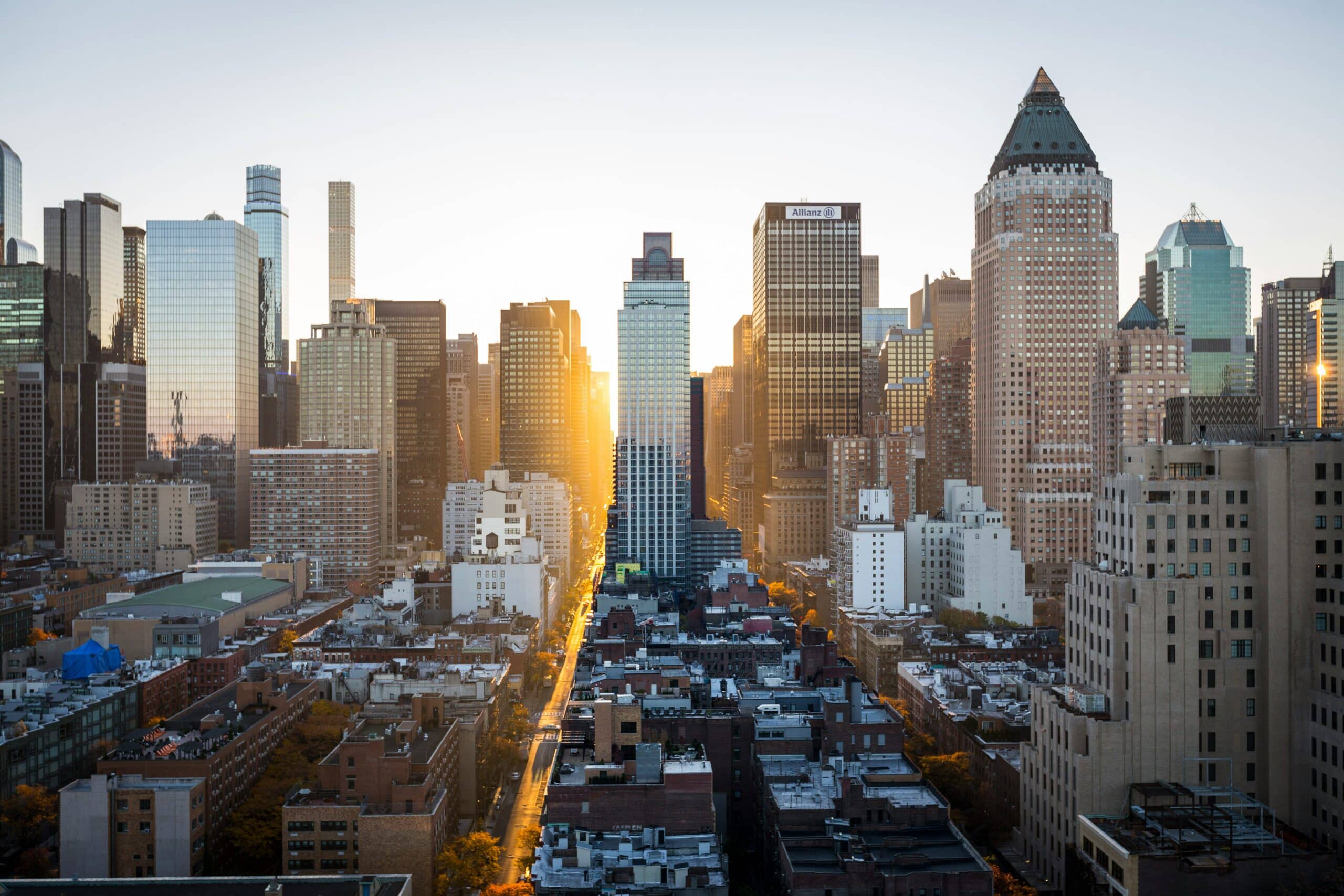 Midtown Manhattan skyline at sunset, with skyscrapers lining the avenue and the low sun reflecting off the facades