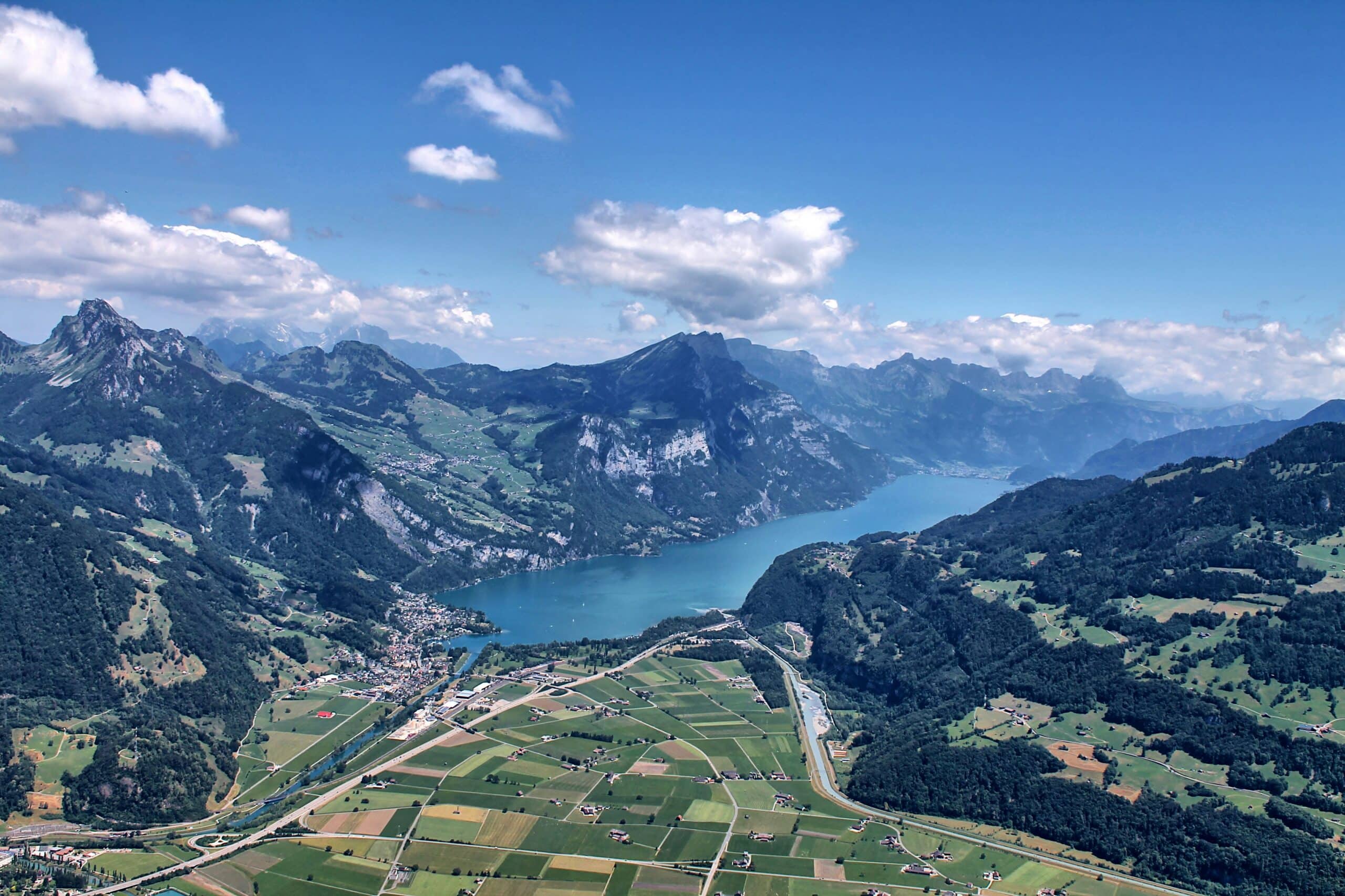 Aerial view of Lake Walen in Switzerland, with an alpine ridge above a valley of farmland and a lakeside village
