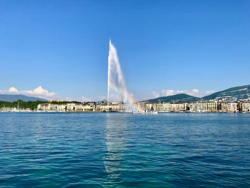 Iconic Geneva Jet d'Eau fountain on Lake Geneva with cityscape background.