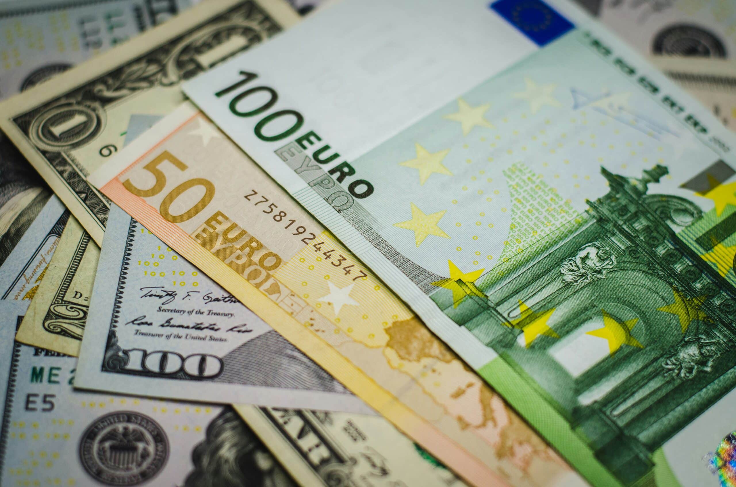 Euro and US dollar banknotes lying overlapped, including a 100 euro, a 50 euro and a 100 US dollar note